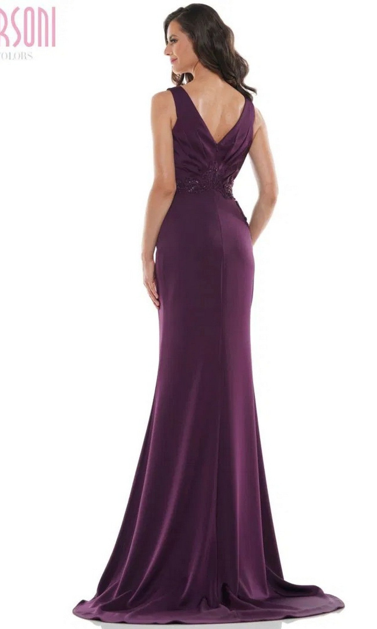 A woman faces away, wearing the Marsoni MV1054—a floor-length, sleeveless formal dress in purple with a V-back, trumpet silhouette, and fitted embroidered bodice.